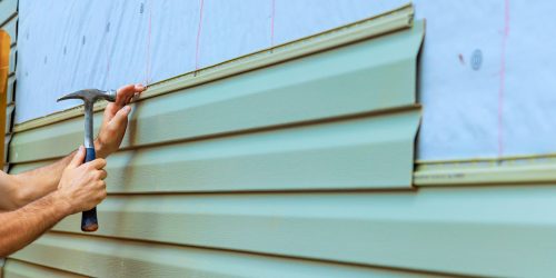 Home improvement project involves installing new siding on an exterior wall with a focus on detail Home improvement project involves installing new siding on an exterior wall with a focus on detail